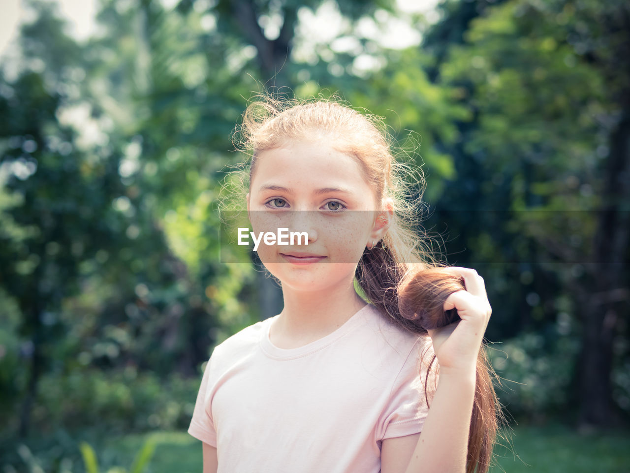 Portrait of girl standing against trees