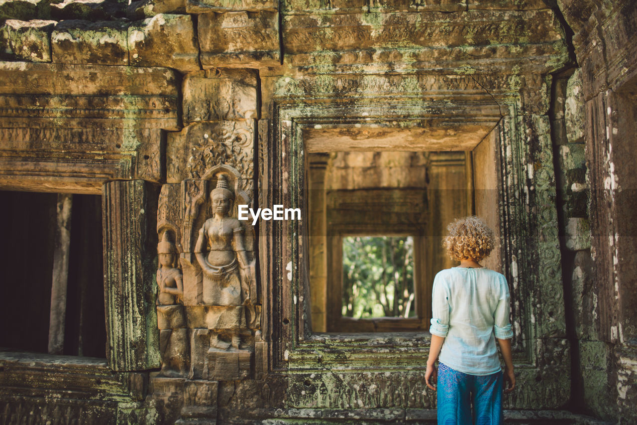 Rear view of mid adult woman standing outside ankor wat temple