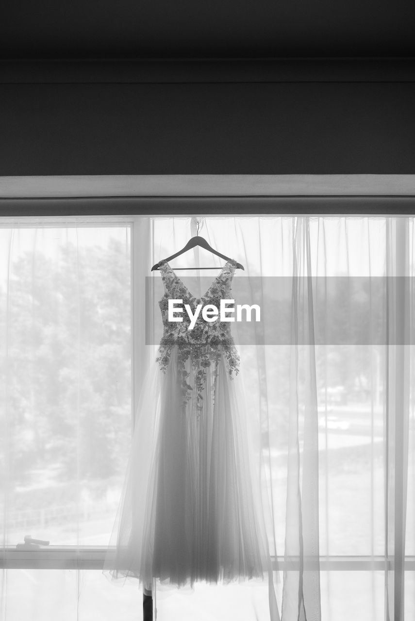 Wedding gown hanging by curtain on wall