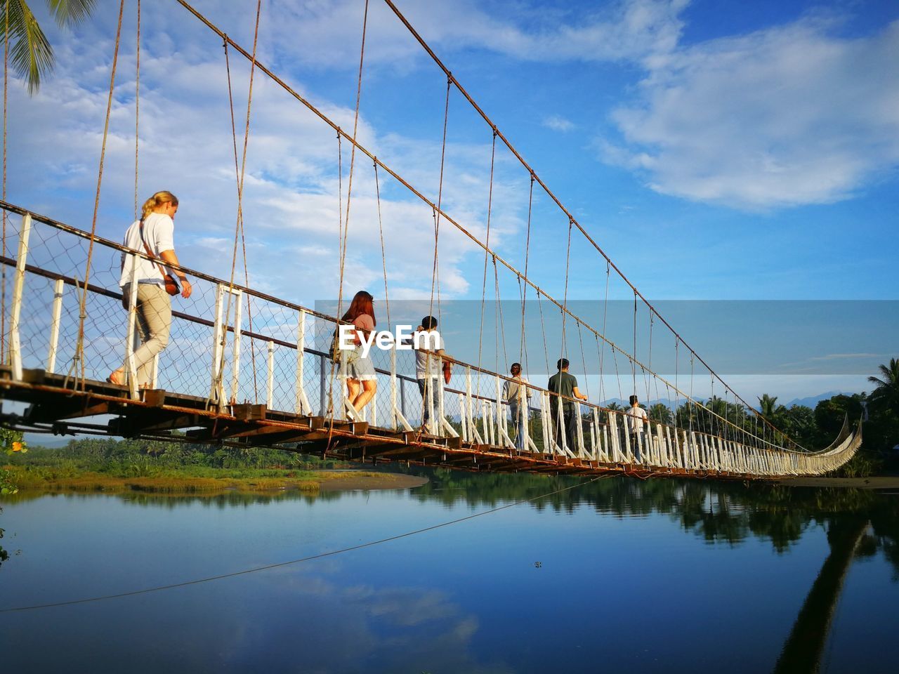 REFLECTION OF PEOPLE ON BRIDGE AGAINST SKY