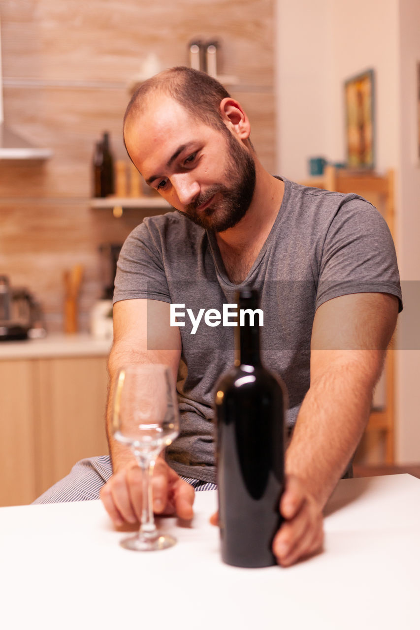 portrait of young man sitting on table at home