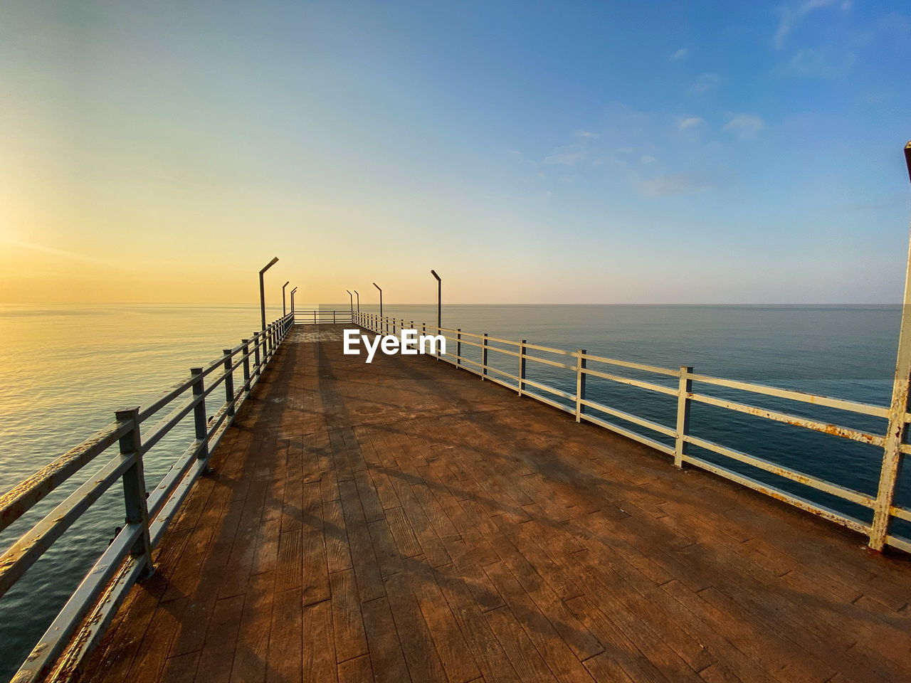 Pier over sea against sky during sunset