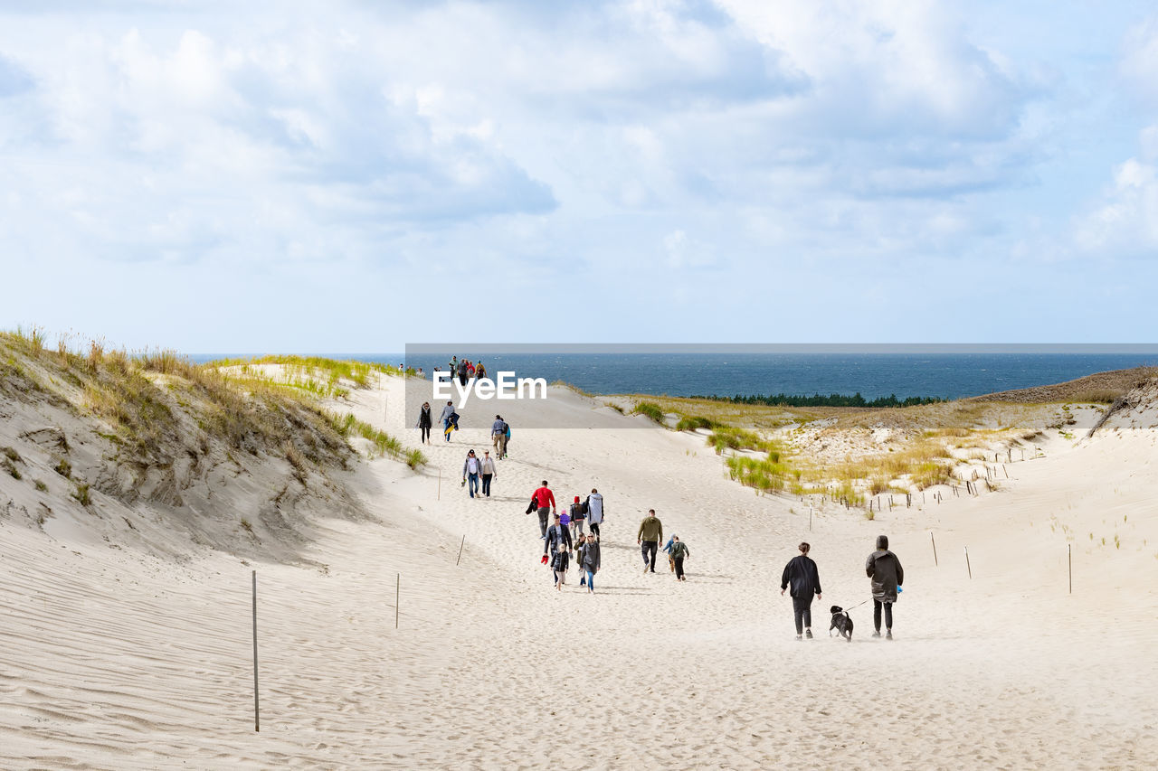 PEOPLE ON BEACH AGAINST SKY