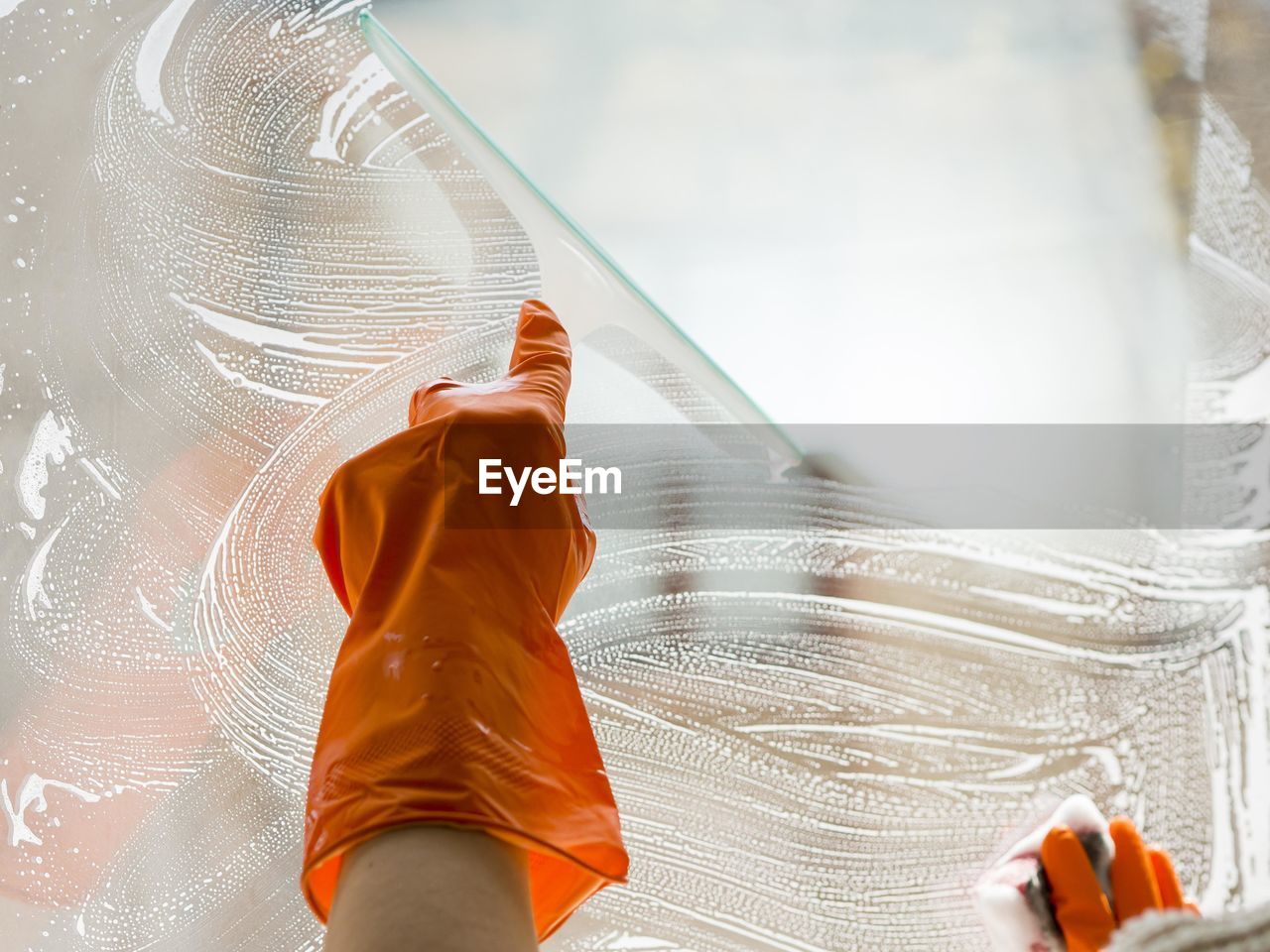 Cropped image of person cleaning glass