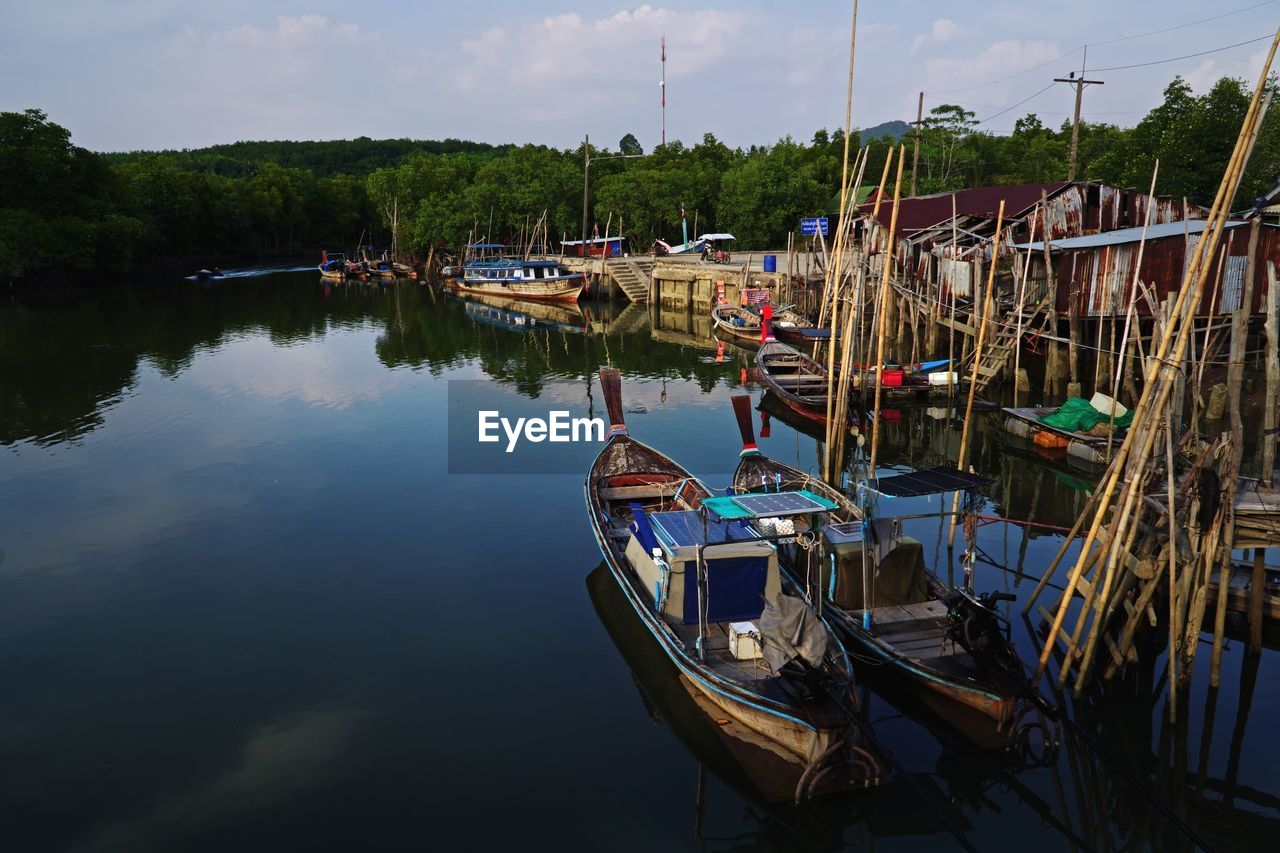 Boats moored at harbor against sky