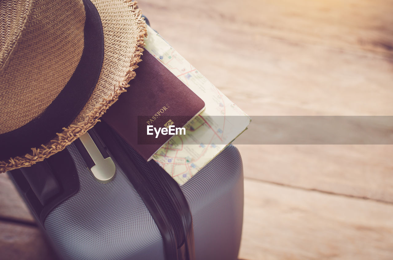 High angle view of suitcase with hat and passport on wooden floor