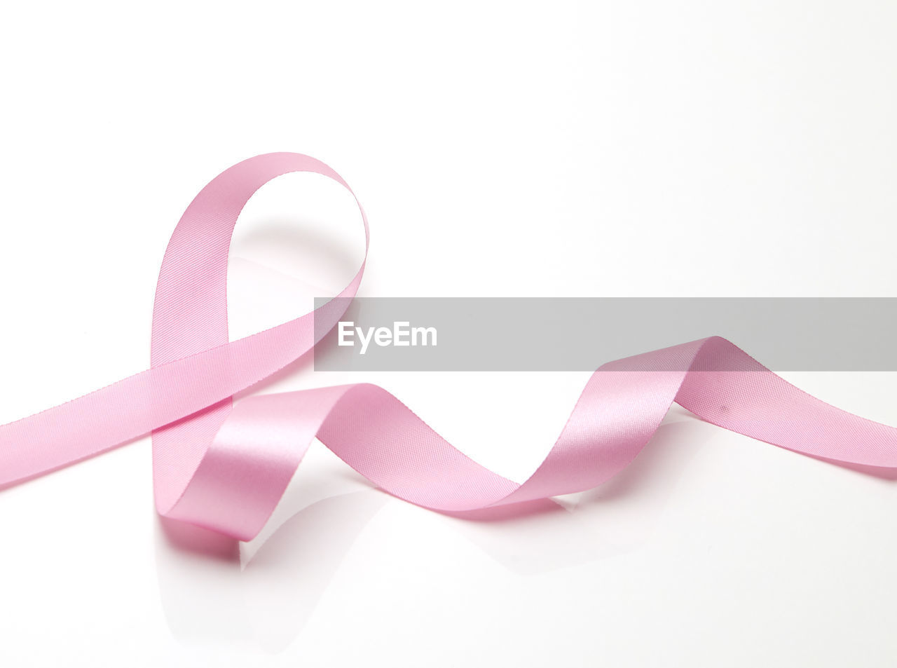 Close-up of breast cancer awareness ribbon over white background