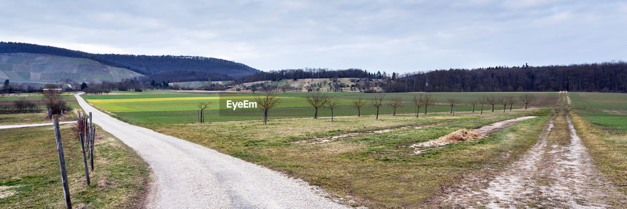 landscape, sky, plant, environment, land, nature, road, rural scene, agriculture, scenics - nature, field, rural area, no people, cloud, tree, waterway, grass, beauty in nature, tranquility, fence, tranquil scene, transportation, farm, reservoir, hill, footpath, day, non-urban scene, outdoors, green, infrastructure, the way forward, dirt road, dirt, travel, soil