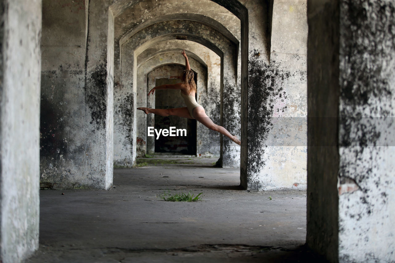 Full length of woman dancing in corridor of abandoned building