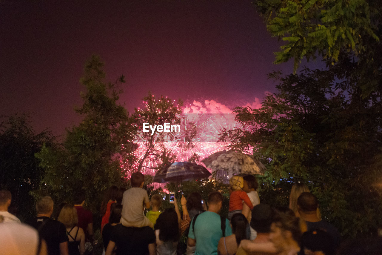 Crowd watching firework display at night