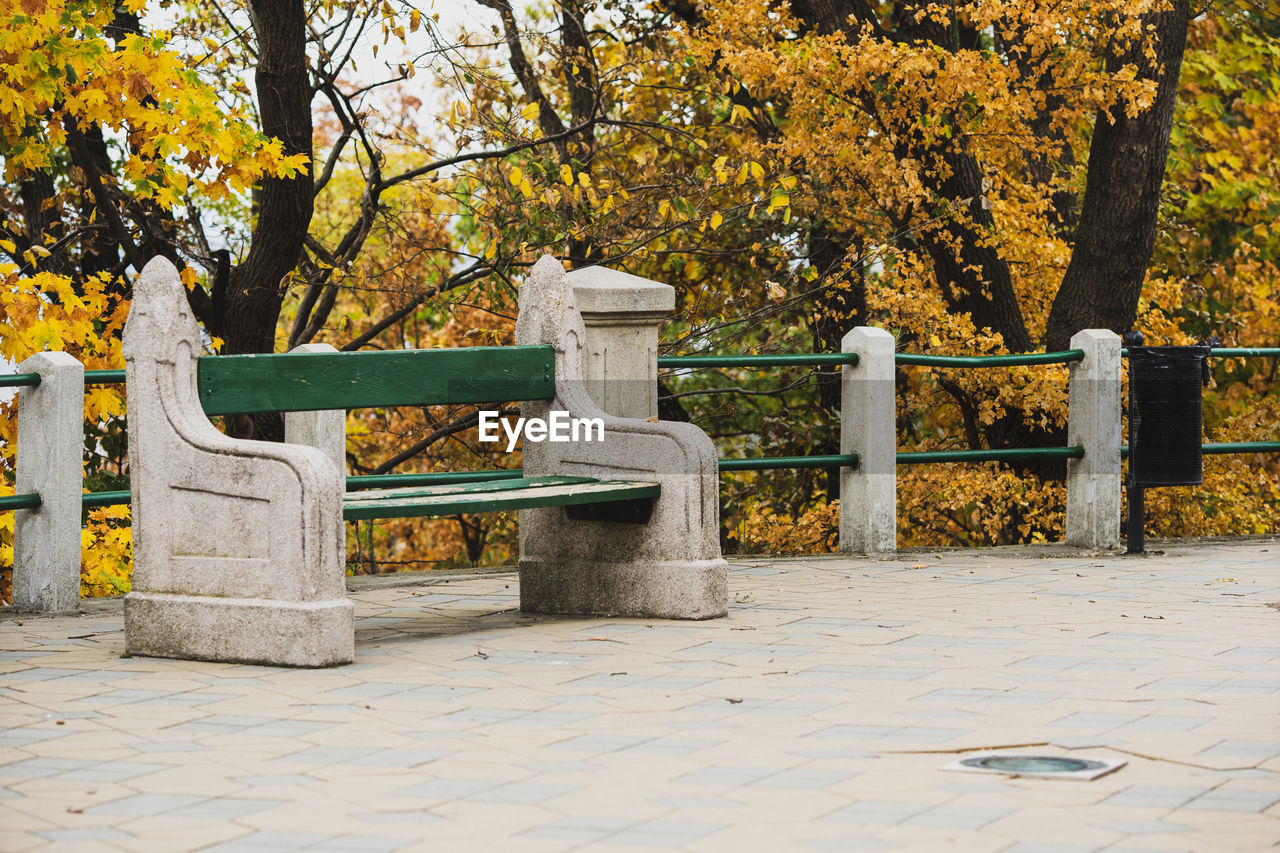 PARK BENCH BY FOOTPATH DURING AUTUMN IN CITY