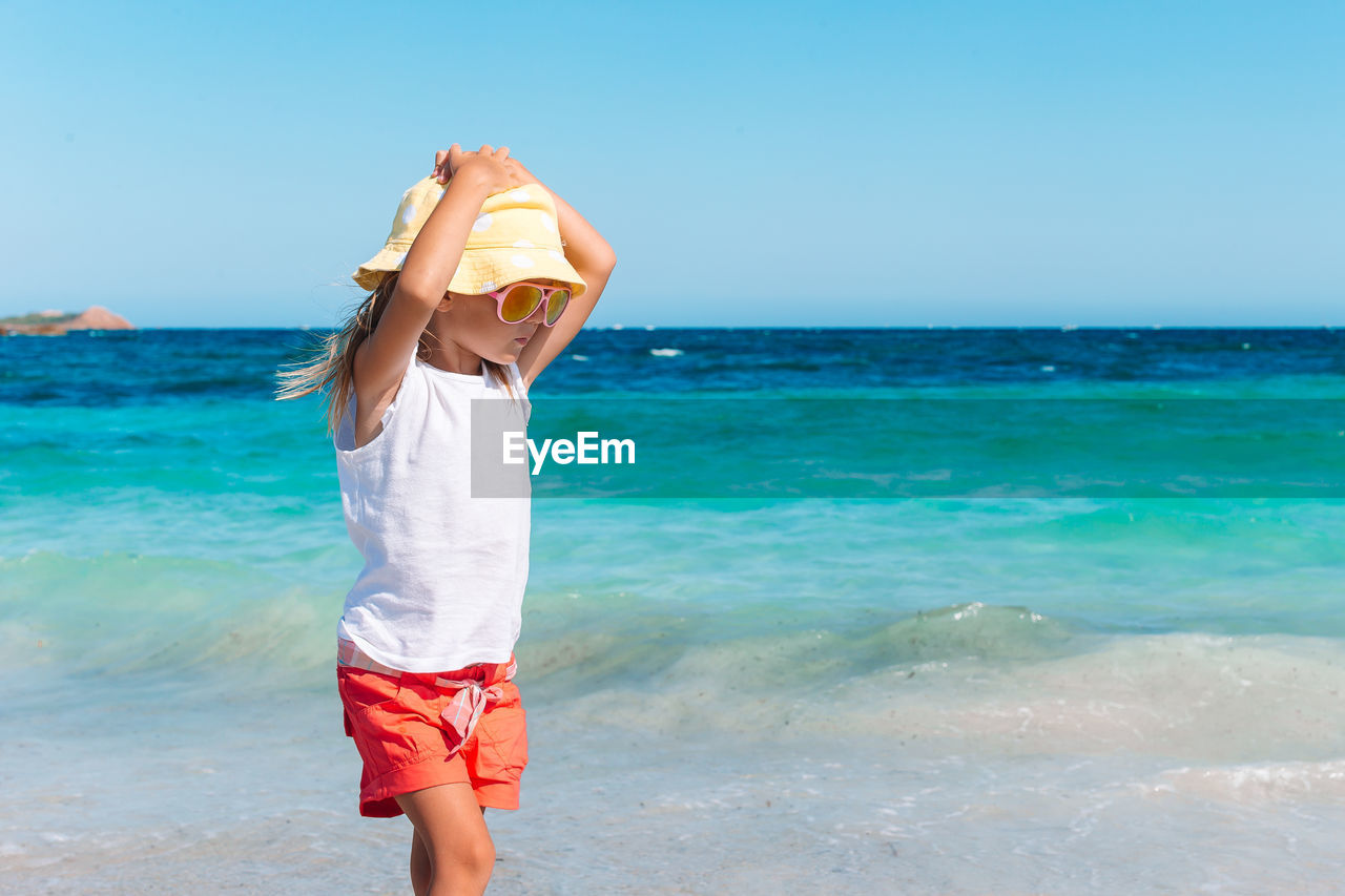 MAN STANDING ON BEACH AGAINST SEA