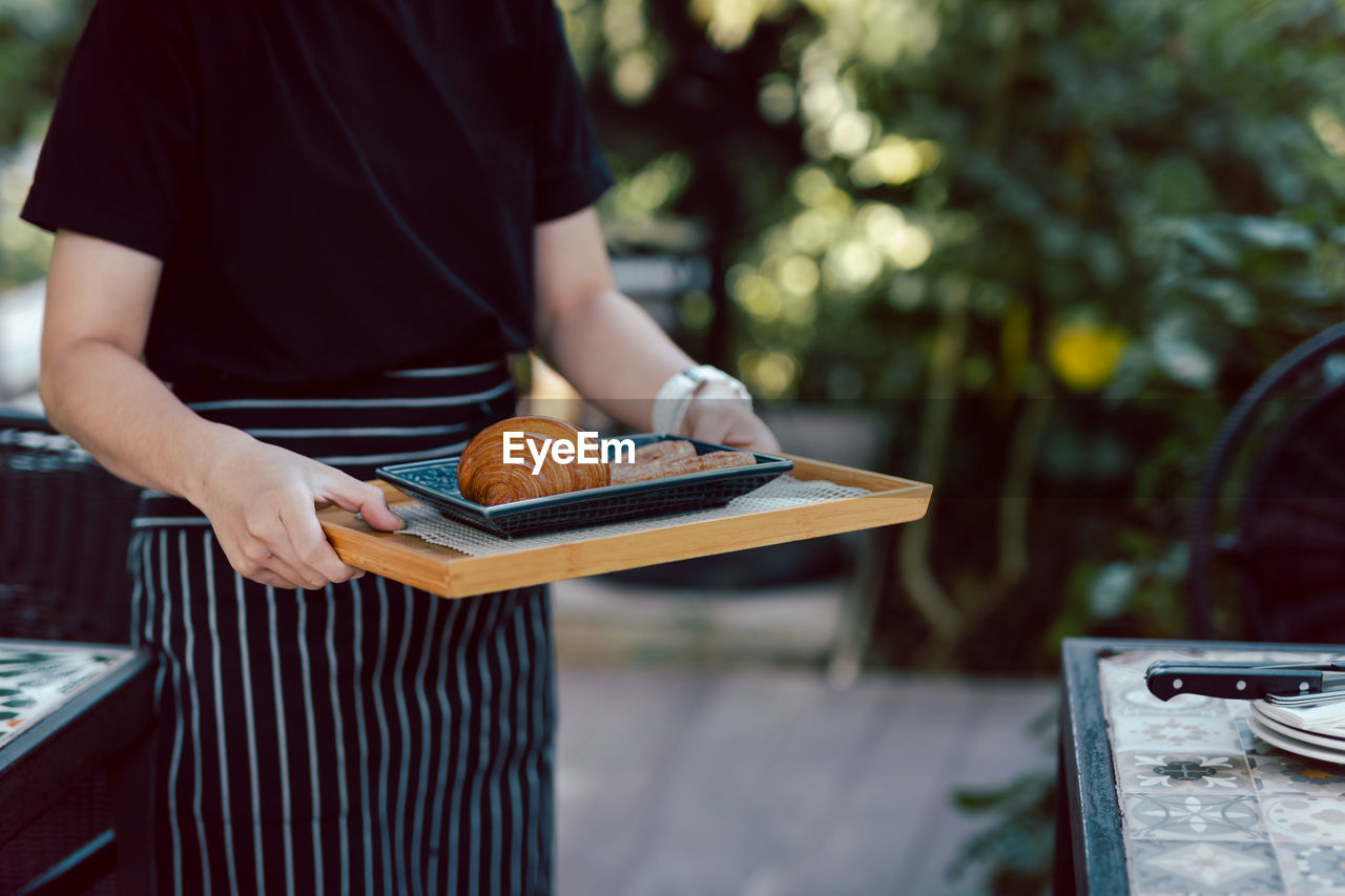 Waitress serving croissants in the coffee shop outdoor.