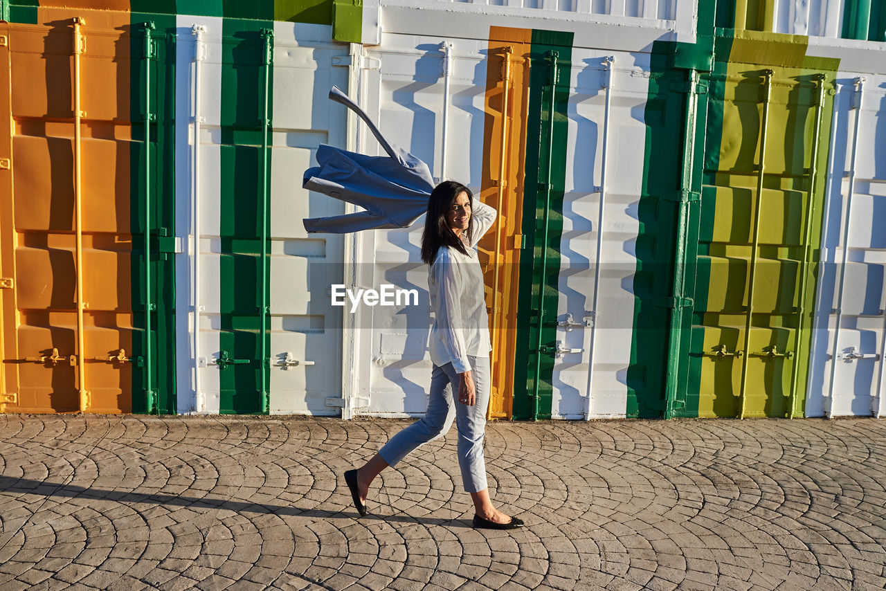 Woman with a jacket on her shoulder walking down the street. person