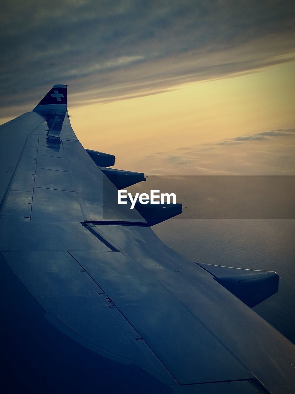 AIRPLANE FLYING OVER LANDSCAPE AGAINST SKY