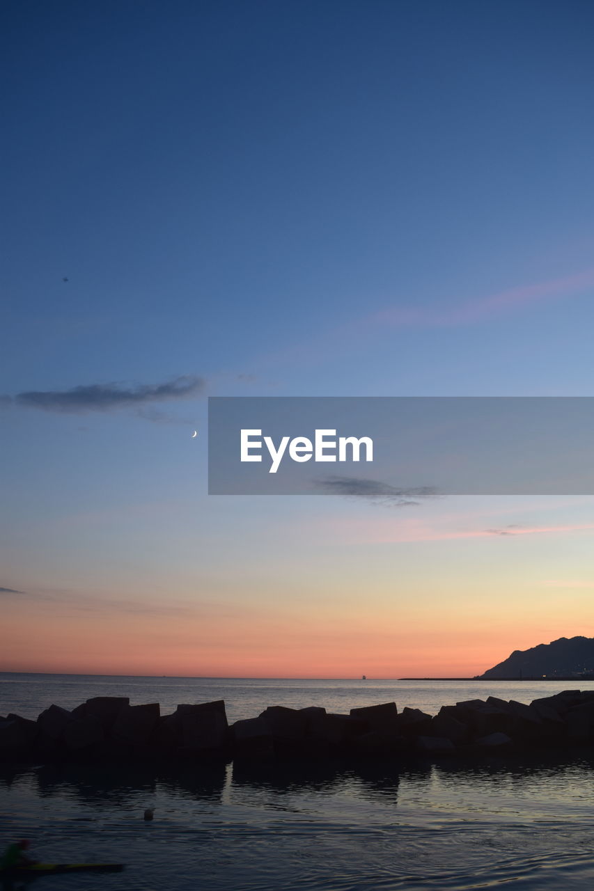 SILHOUETTE ROCKS IN SEA AGAINST SKY DURING SUNSET