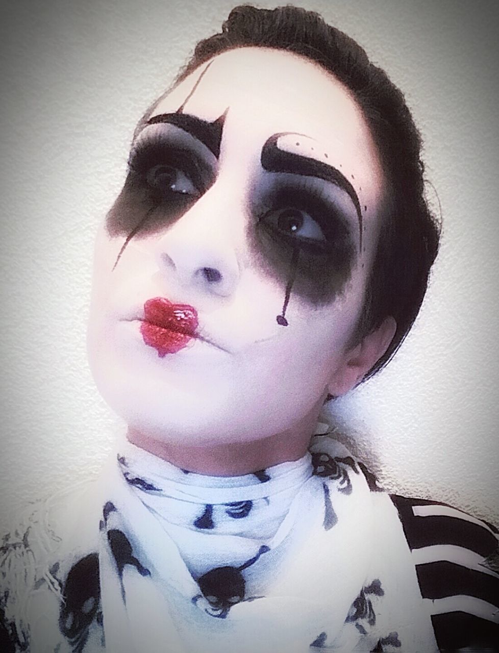 Close-up of woman in clown costume and make-up against white background