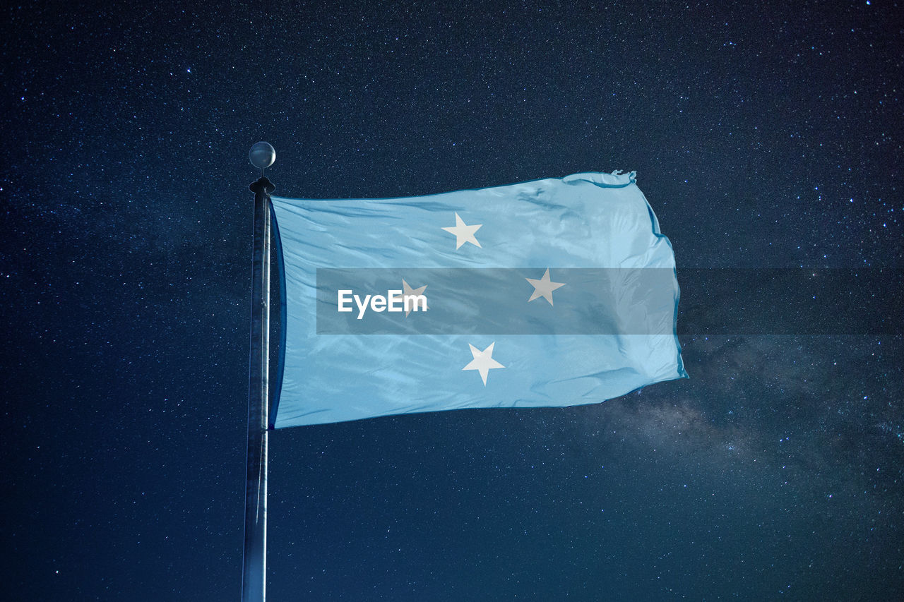 Low angle view of micronesian flag against star field sky