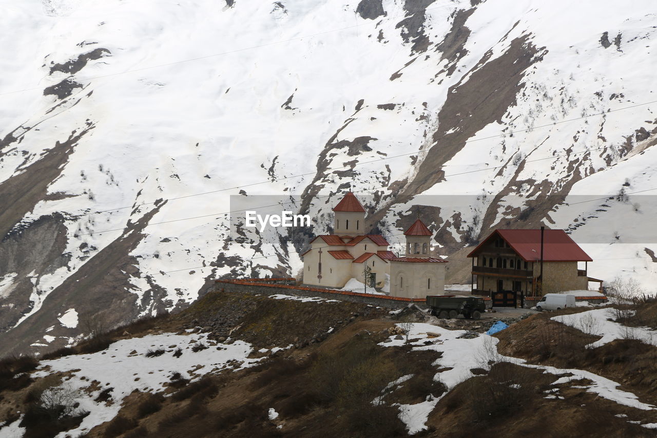 SNOW COVERED HOUSES AND BUILDINGS BY MOUNTAIN