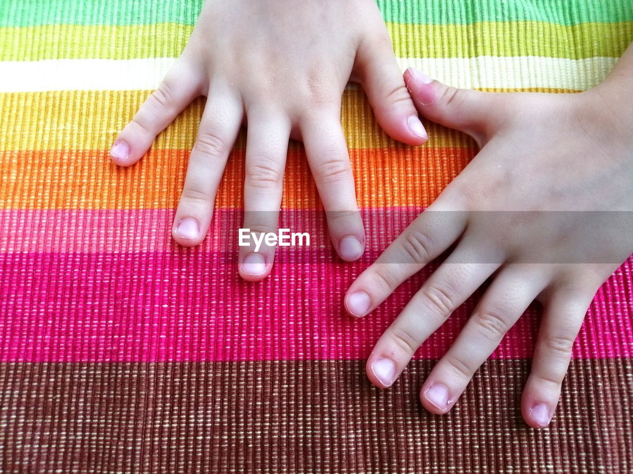 Cropped hands on multi colored tablecloth