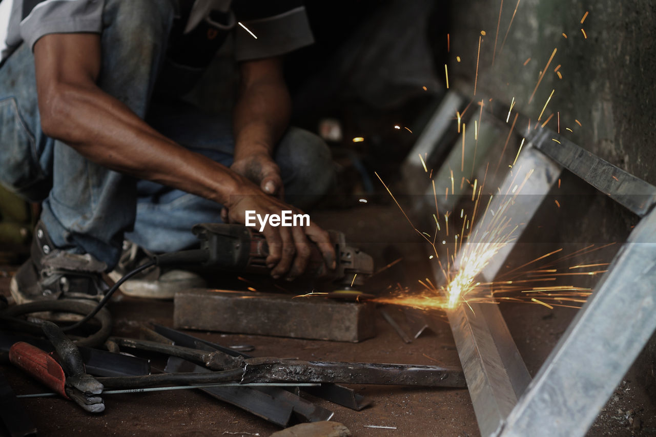 Low section of male worker grinding at workshop