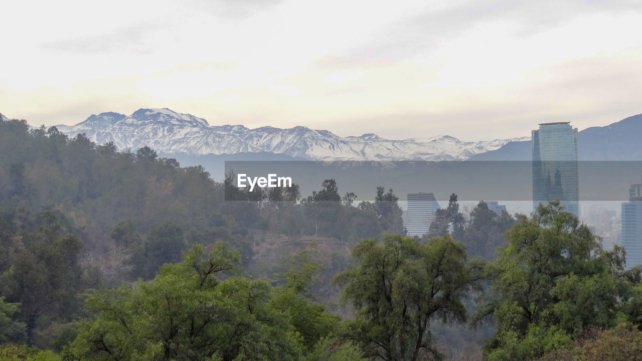 Scenic view of trees and buildings against mountain and sky