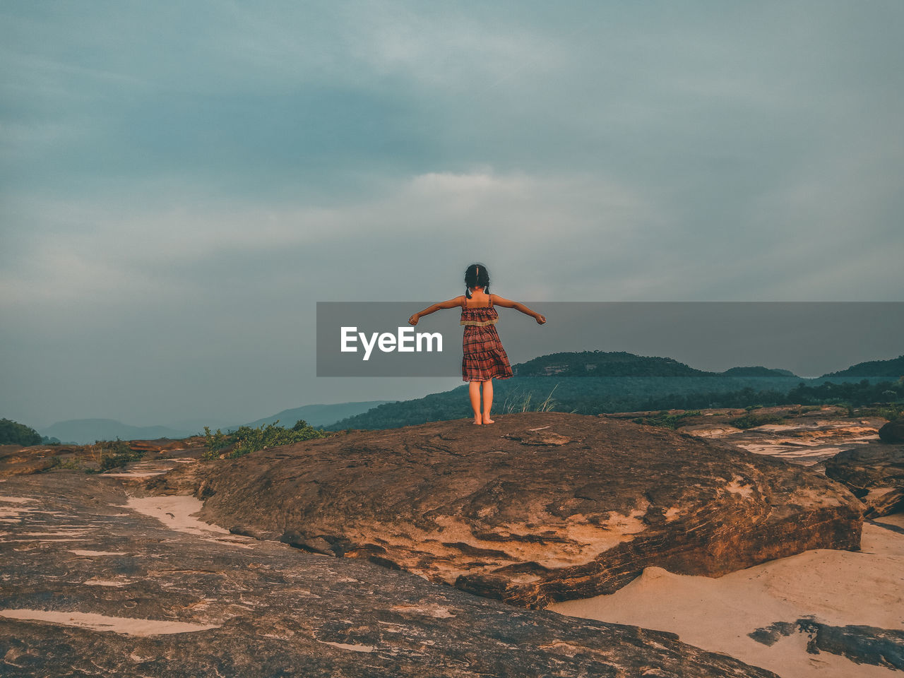 REAR VIEW OF PERSON STANDING ON ROCK