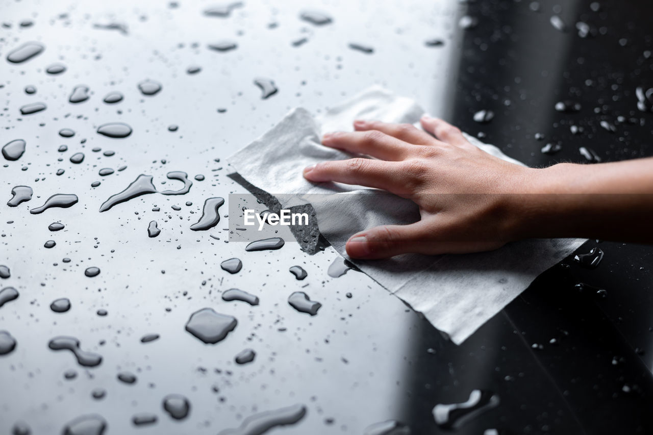 CLOSE-UP OF WET HAND WITH RAINDROPS