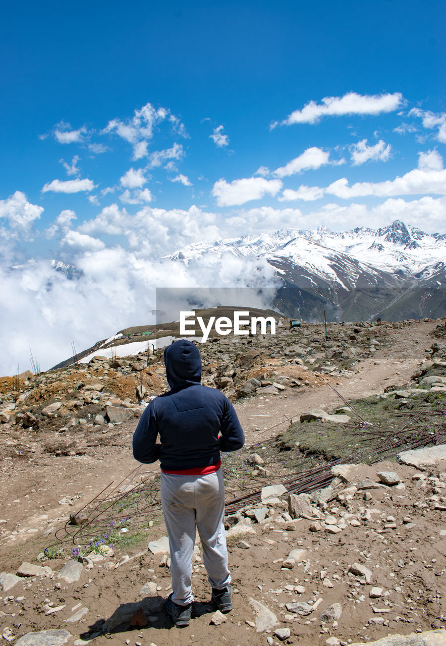 Rear view of boy walking on mountain against sky