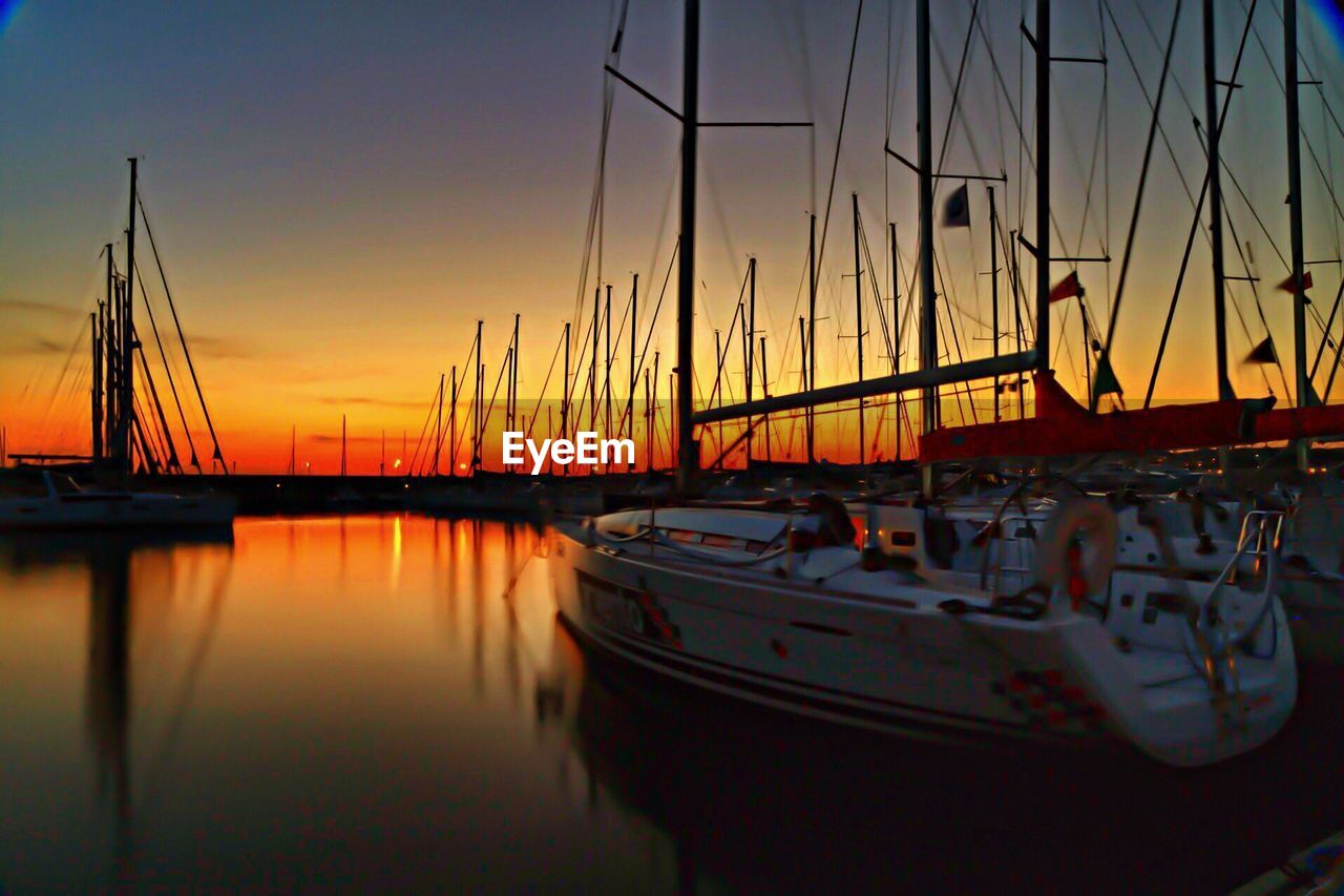 SAILBOATS MOORED AT HARBOR