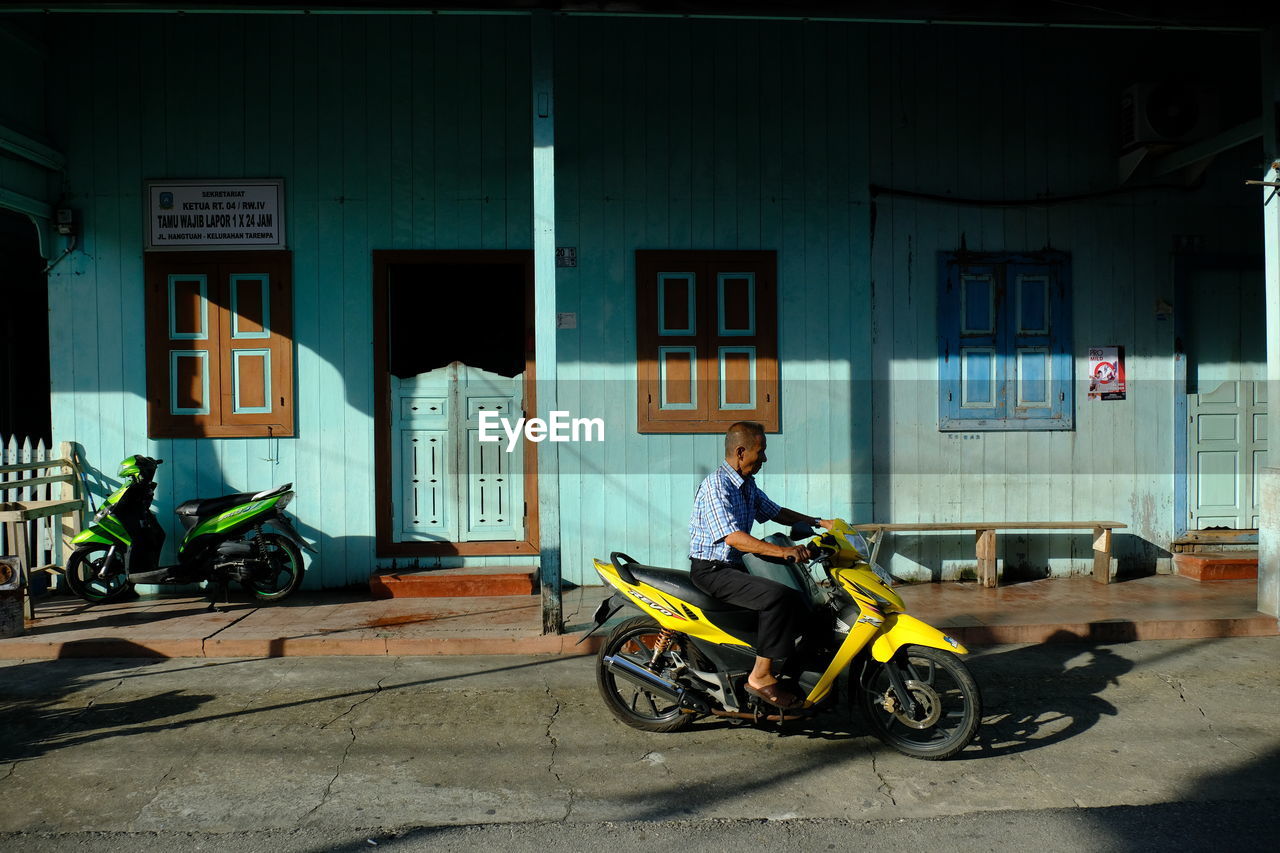 MAN CYCLING ON STREET AGAINST BUILDING