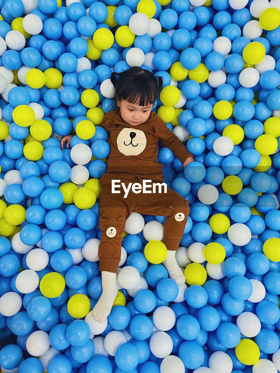 Full frame shot of a toddler lying on multi colored balls