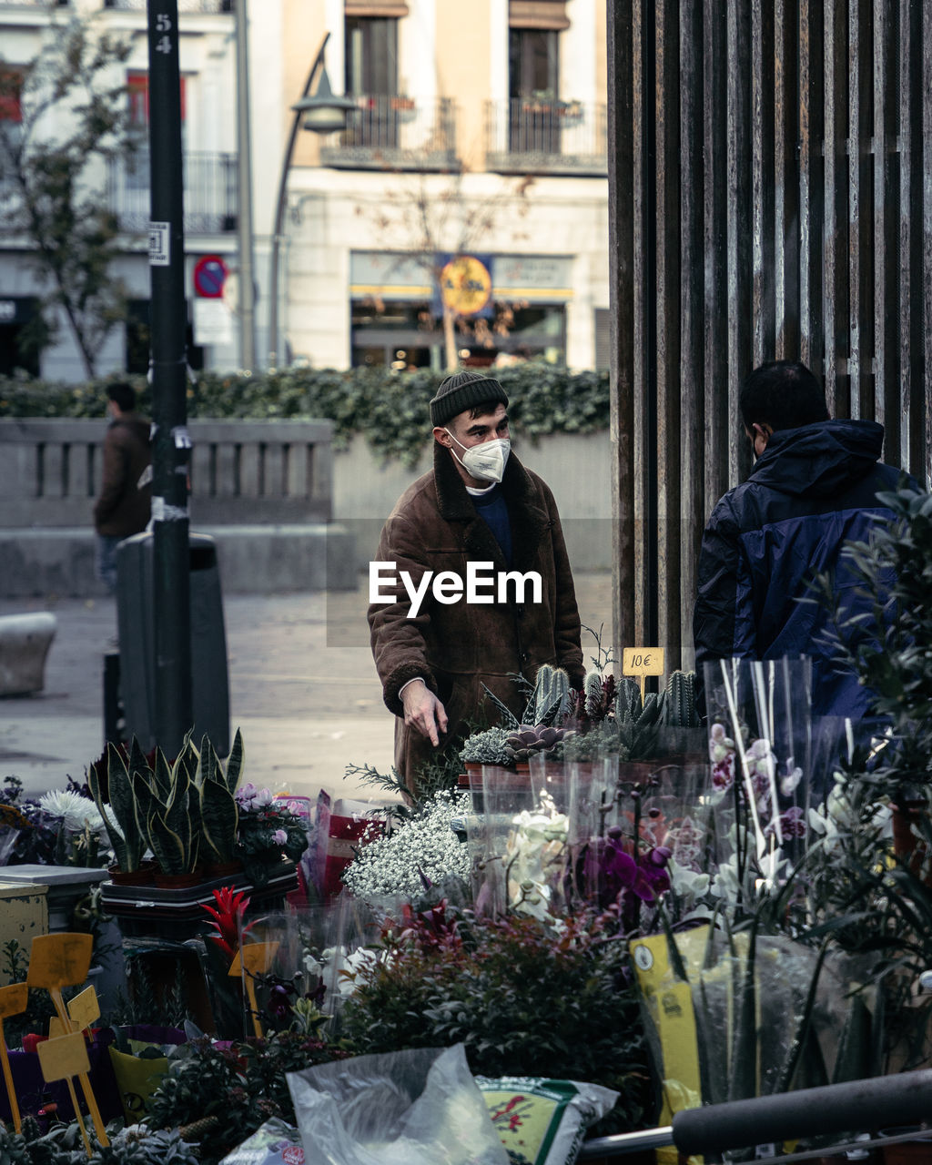 Man wearing mask standing by flower shop