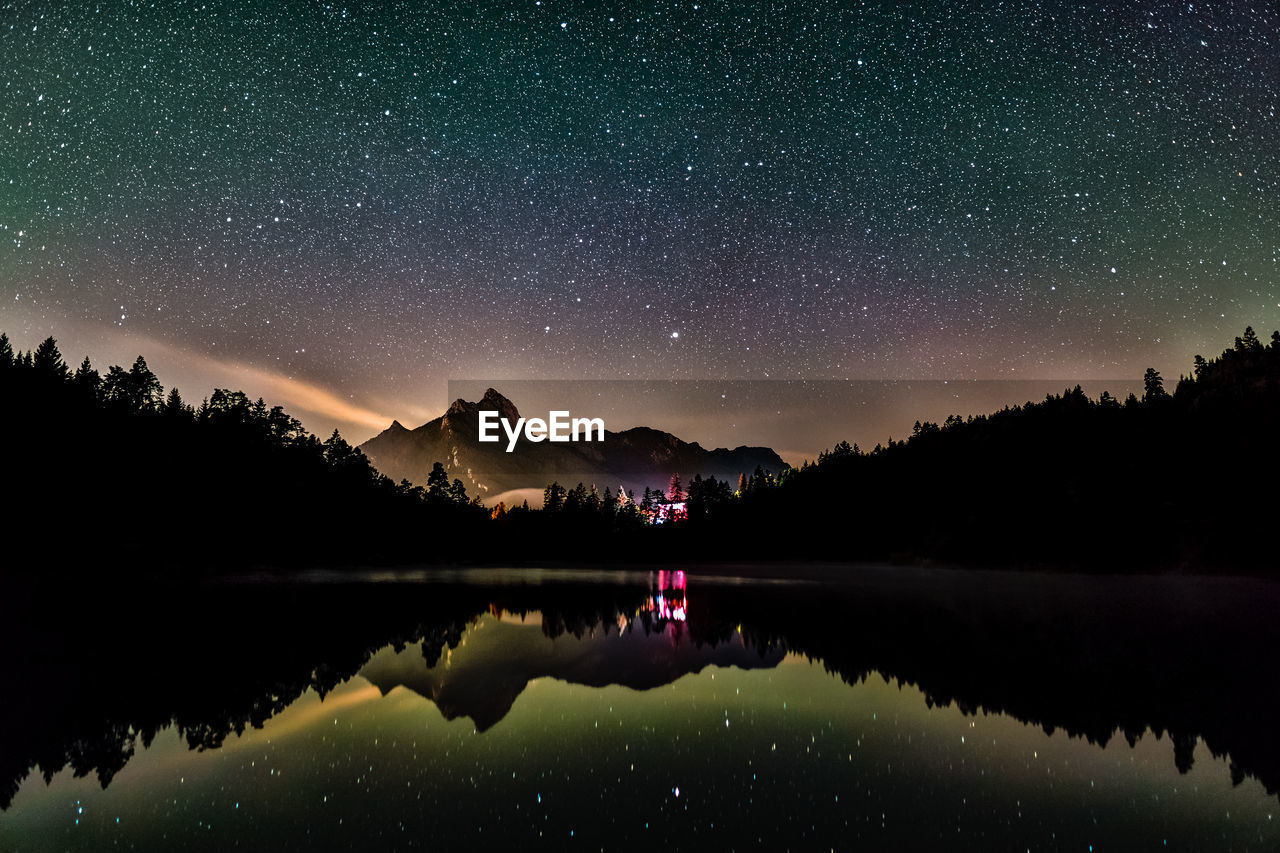 Night sky reflection in lake urisee with alps mountains in background