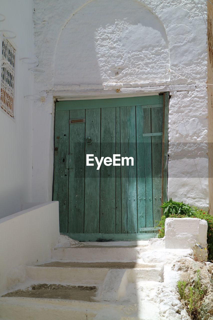 Closed wooden door of white building