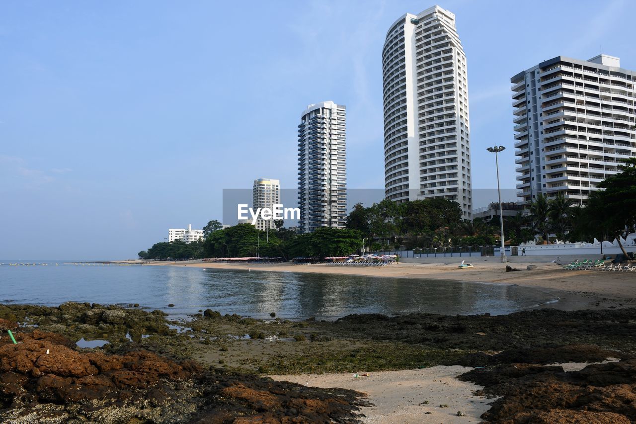 Buildings by sea against sky in city