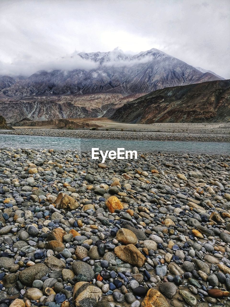 Colourful stones on the riverbed against the backdrop of the himalayas