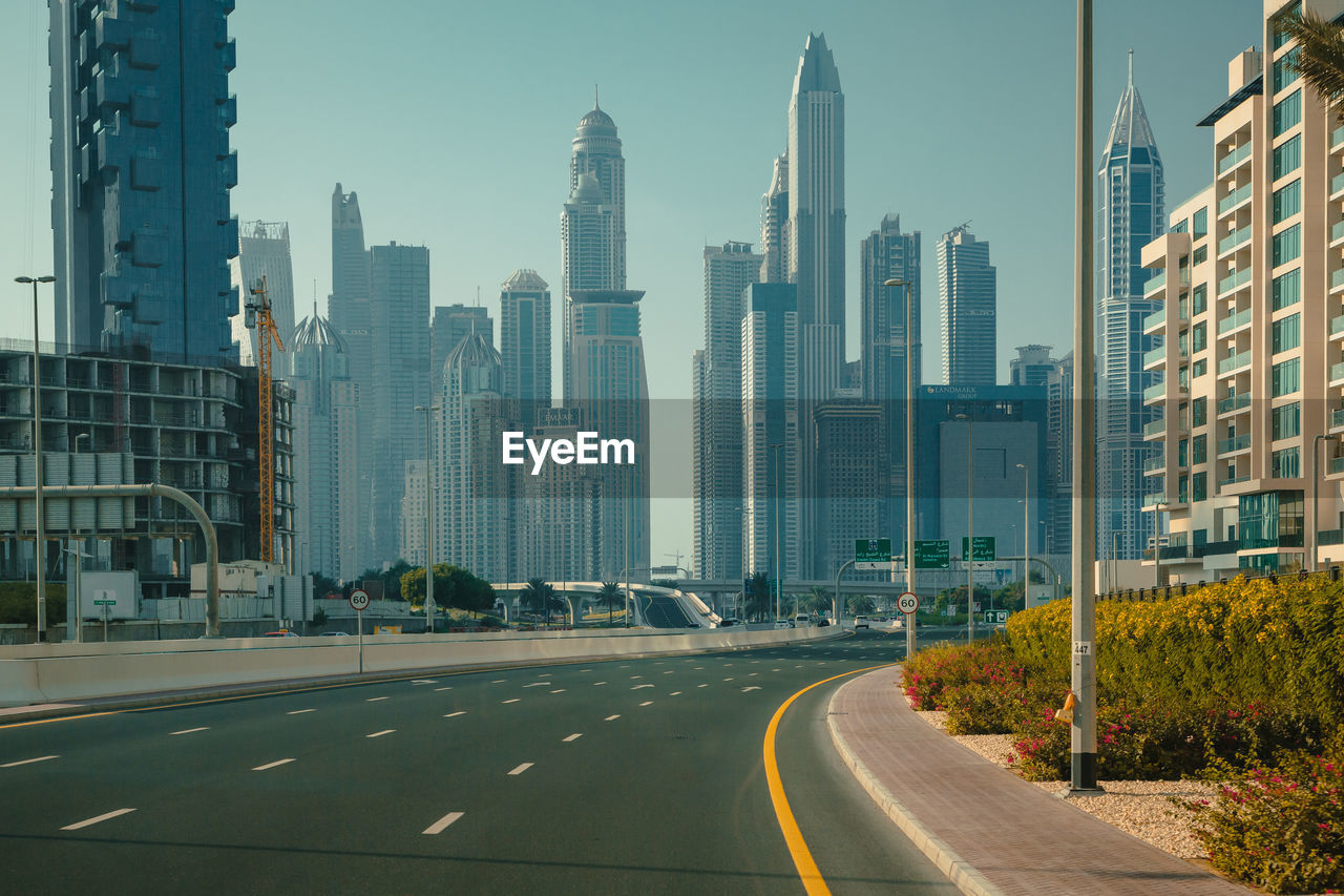 Road by buildings in city against sky. united arab emirates. dubai city view highway.