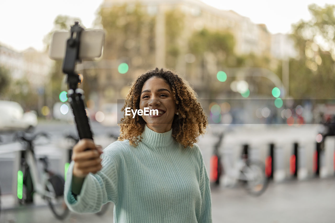 Happy woman filming through smart phone on tripod