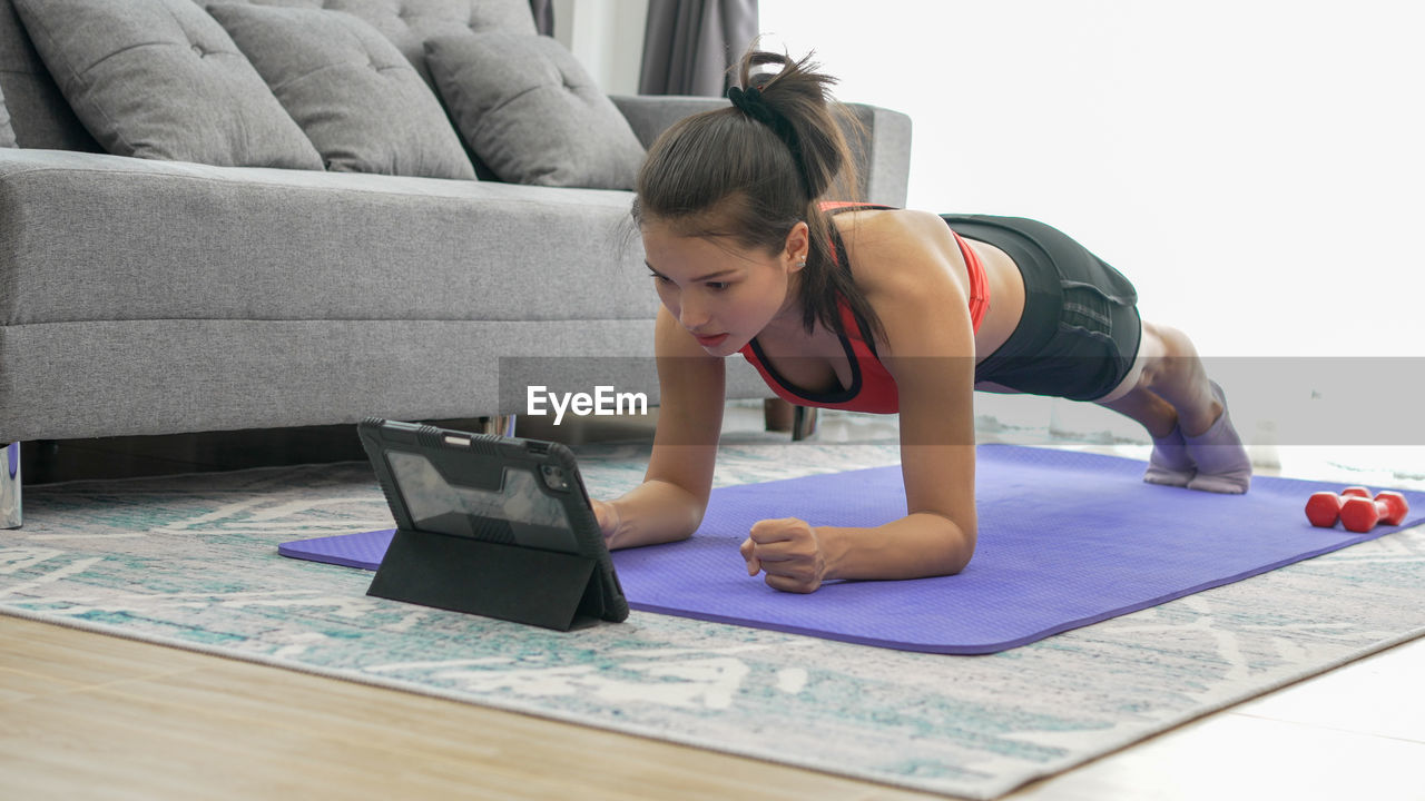 Young woman doing plank position at home
