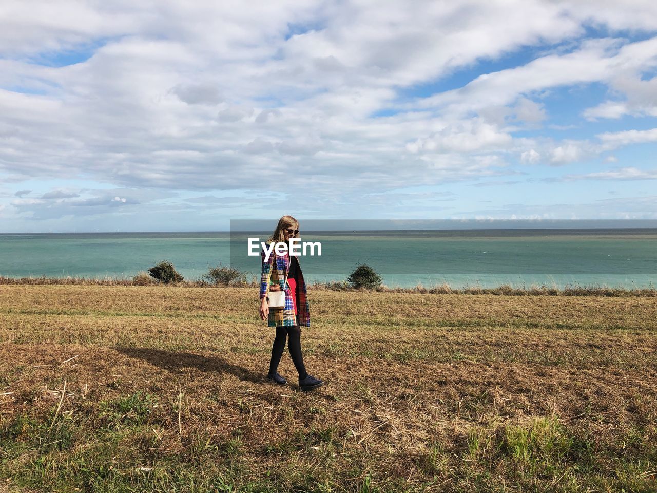 Full length of woman walking by sea on land