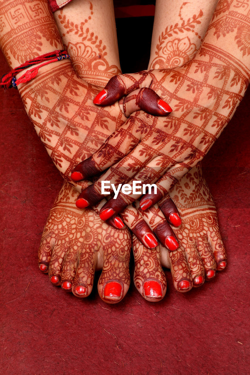 Lady hand feet with indian heena in indian wedding with red background