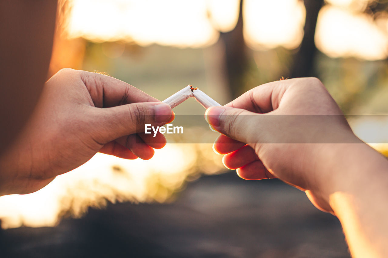 Men hand caught a burning cigarette causing smoke, concept stop smoking.