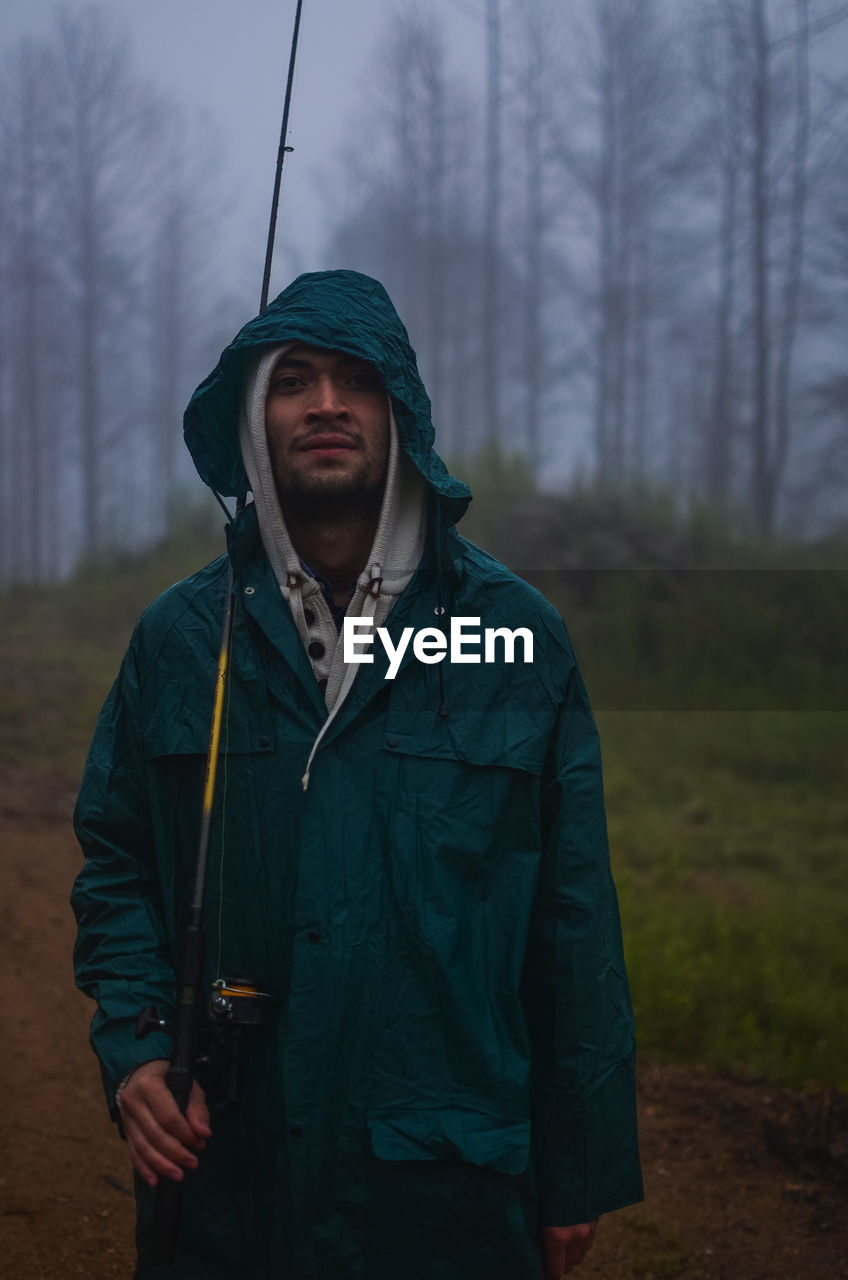 Young man standing in forest during winter