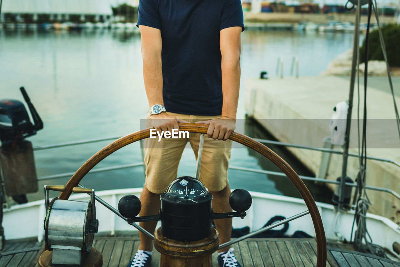 Low section of man holding steering wheel in boat