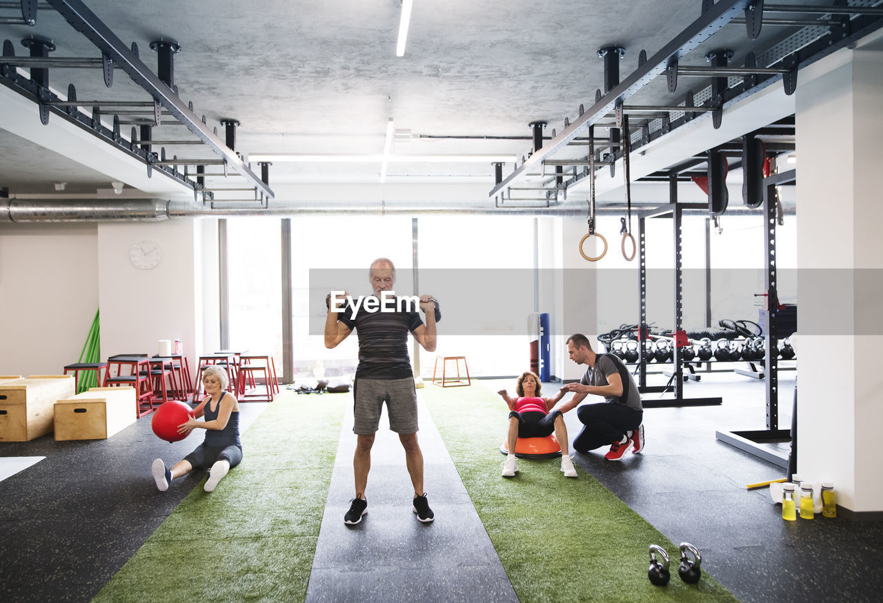 Group of fit seniors with personal trainer in gym