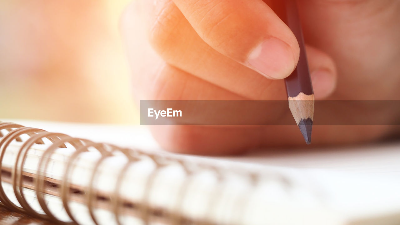Close-up of hand writing in book