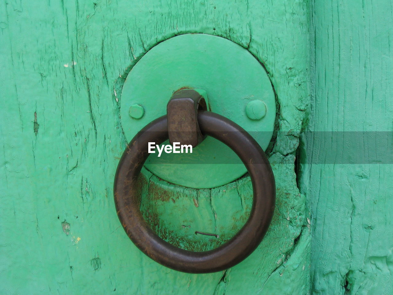 CLOSE-UP OF OLD DOOR KNOCKER ON GREEN WALL