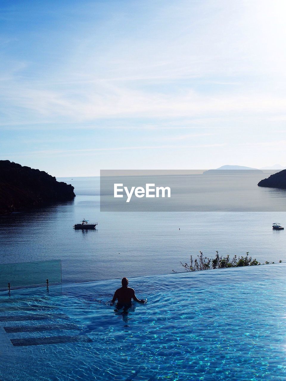 Man on infinity pool by sea against sky