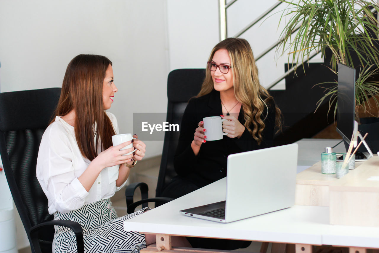 Businesswoman having discussion while having coffee at office